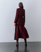 Model wearing red blazer, red skirt, and boots. standing facing away