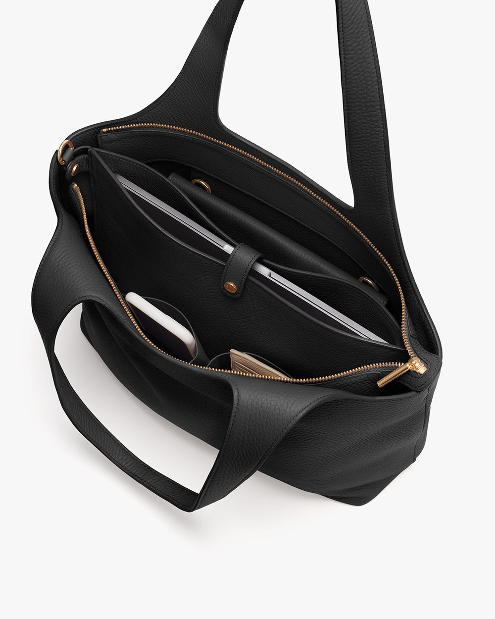 Open handbag with various items inside, including a laptop and a phone.