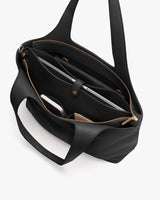 Open handbag with various items inside, including a laptop and a phone.