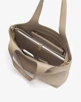 Open handbag with compartments holding a laptop, tablet, glasses, phone, and notebook.