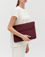 Person holding a large leather laptop sleeve