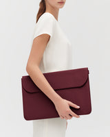 Person holding a large leather laptop sleeve