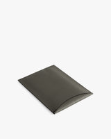 Rectangular leather laptop sleeve with a curved flap closure.