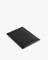 Rectangular laptop sleeve with a slightly open flap on flat surface.