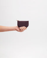 Hand holding a small zippered wallet against a plain background.