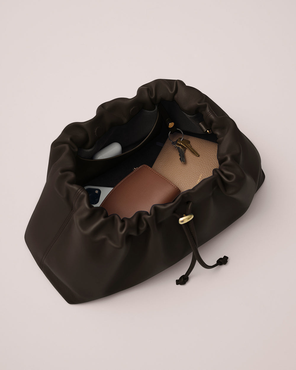 Dia Bag Open drawstring bag with wallet, keys, and phone inside.