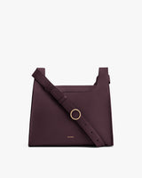 Shoulder bag with a strap and small metallic ring on the front.