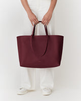 Person holding a large tote bag, wearing light pants and shoes.