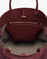 Open handbag showing zippered interior pocket and handles.
