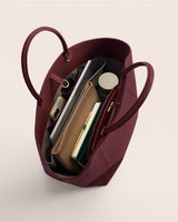 Open tote bag with books, pouches, and tech items inside.