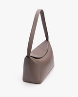 Shoulder bag with a curved flap and long strap shown at an angle