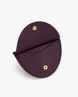 Circular pouch with a button closure and textured surface.