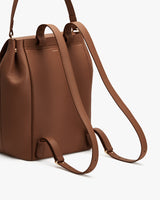 Backpack with long adjustable straps laid out on the surface.