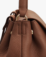 Close-up of a leather backpack with a metal ring detail.