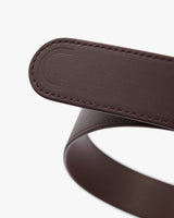 Close-up of a leather belt with embossed logo on buckle.