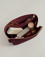 Open makeup bag with various cosmetics and a brush inside.