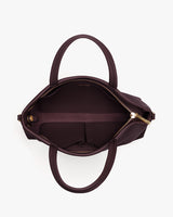 Open handbag with two handles and a zipper, showing interior compartments.