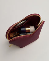A small zippered pouch with several cosmetic items inside.