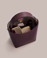 Open handbag with phone, small wallet, and bottle inside.