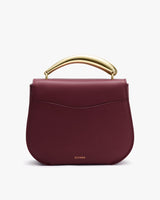 Handbag with curved metal handle on top.