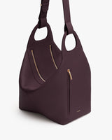 Large tote bag with zippers and curved handles.