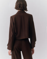 Person wearing a long-sleeve jacket and pants, seen from the back.