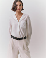 Person wearing a button-up shirt with a patterned pocket and belted trousers.