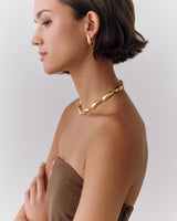 Person wearing earrings and a necklace, looking to the side.