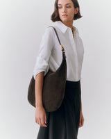 Person wearing a shirt and skirt, holding a shoulder bag.