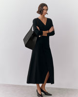 A woman wearing a long dress with a large shoulder bag and heels.