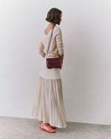 Person wearing a long skirt, sweater, and sandals with a shoulder bag.