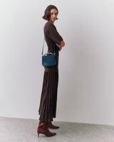 Person with crossbody bag in long dress and boots.