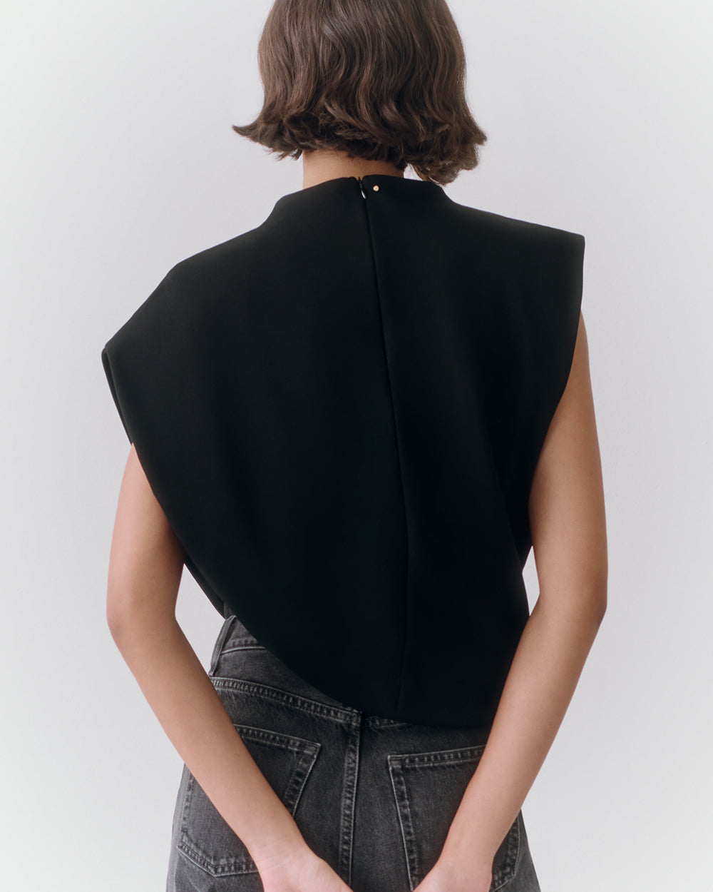 Person wearing an asymmetrical top with arms behind back