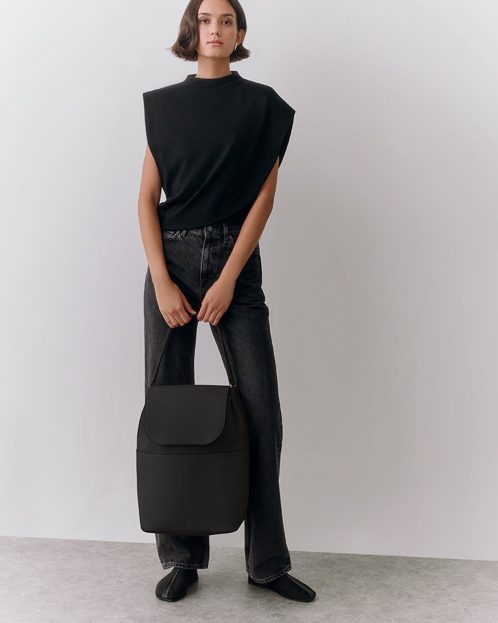 Leather Backpack 16-inch Person in sleeveless top and jeans holding a backpack.