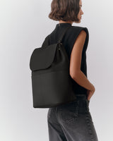 Person carrying a large backpack over one shoulder