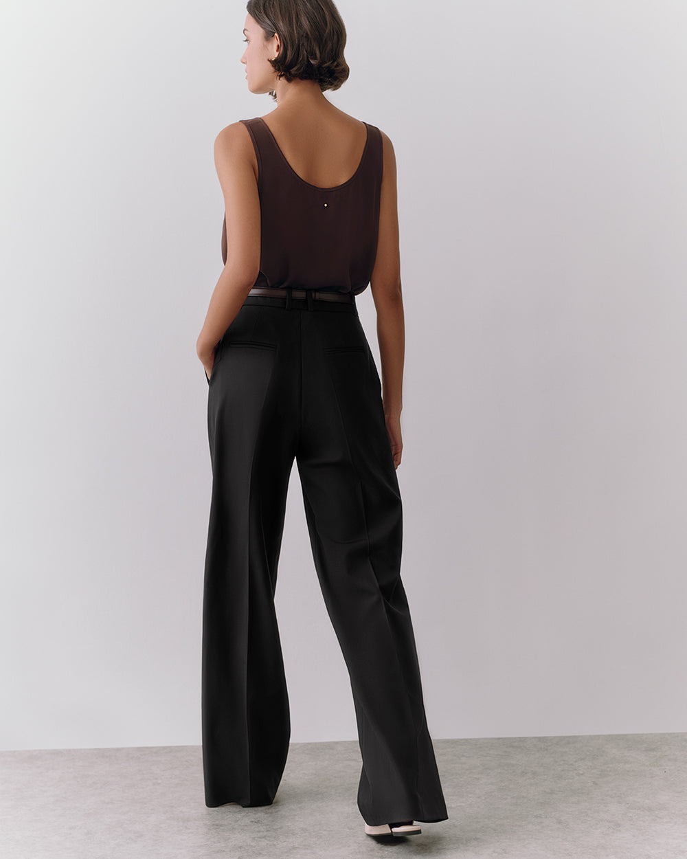 Person wearing a sleeveless top and trousers, standing on a plain background.
