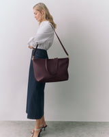 Person standing with shoulder bag and wearing long skirt and heels