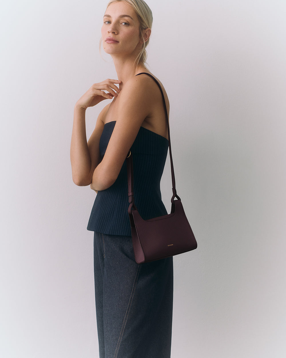 Mini Double Loop Bag Person posing with a shoulder bag, wearing a strapless top and pants.