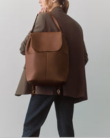 Person in a suit holding a large backpack over shoulder.