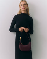 Person in a long dress holding a handbag.