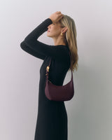 Person with shoulder bag wearing a long-sleeve dress, looking upwards.