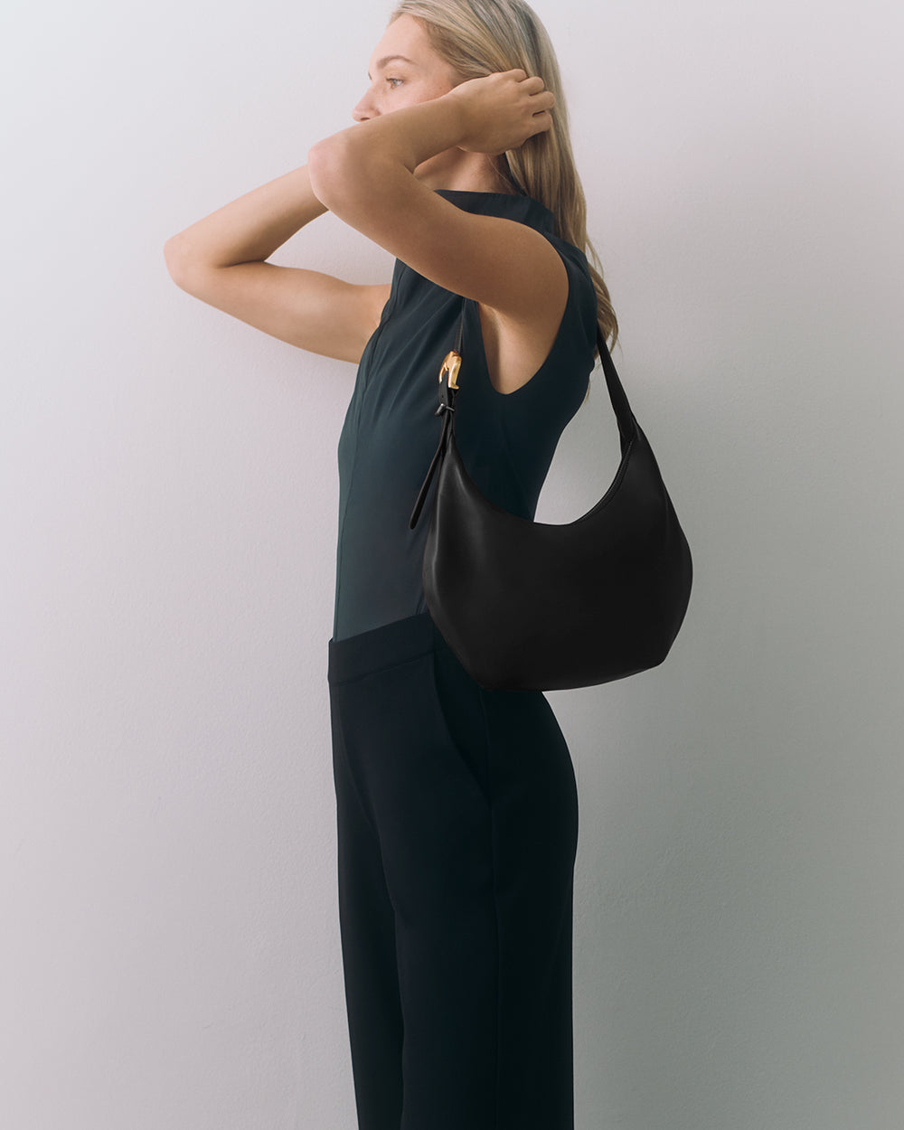 Person posing with a handbag on their shoulder.