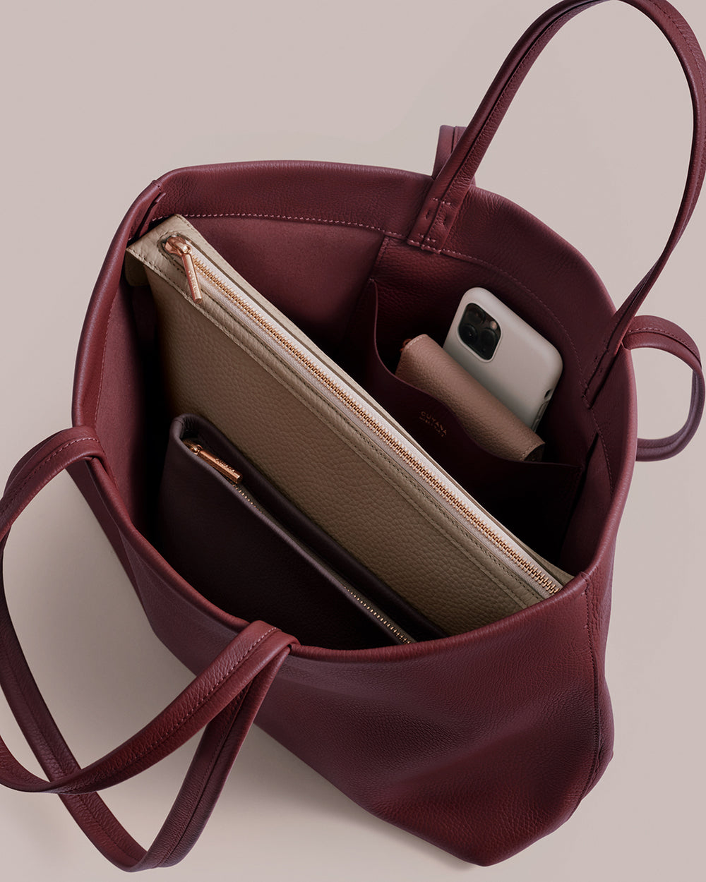 Open tote bag with a laptop sleeve, wallet, and smartphone inside.