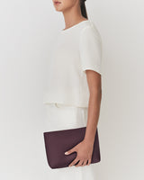 Person holding a pouch with one hand, wearing a plain short-sleeve top and skirt