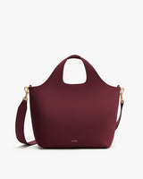 Handbag with a wide handle and detachable shoulder strap.