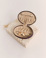 Open zippered jewelry case on a textured surface with rings nearby.
