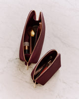 Two open makeup bags with brushes and cosmetic products inside.