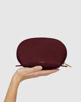 A hand holds a small pouch with a zipper closure.