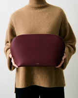 Person holds a large pouch in front of their chest.