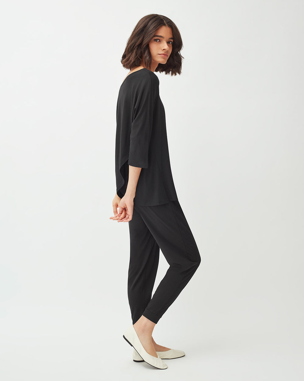 Woman walking in studio wearing a casual outfit and heels.